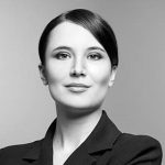 Black and white portrait of a beautiful elegant professional woman standing with folded arms in a stylish jacket looking at the camera with an enigmatic smile, with copy space