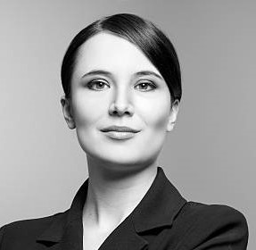 Black and white portrait of a beautiful elegant professional woman standing with folded arms in a stylish jacket looking at the camera with an enigmatic smile, with copy space